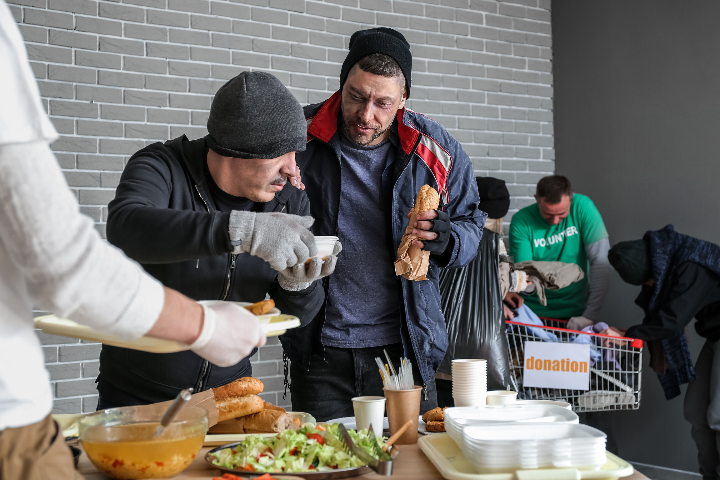 Volunteer Giving Food to Homeless People in Warming Center